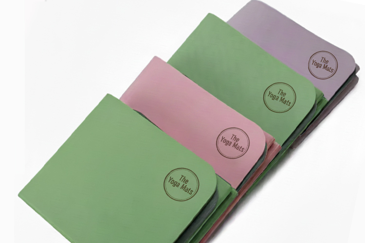 A stack of four foldable TPE yoga mats in assorted colors including green, pink, and purple, ideal for travel.