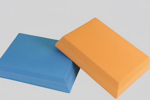 A blue and an orange rectangular high-density EVA foam block side-by-side, used for yoga and physical therapy.