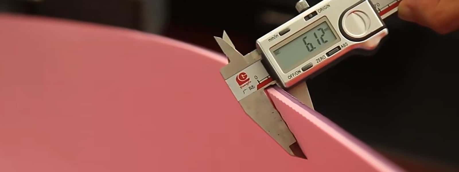 A close-up shot of a digital caliper measuring the thickness of a pink yoga mat, showing a precise reading of 6.12 mm to ensure product quality at the factory.