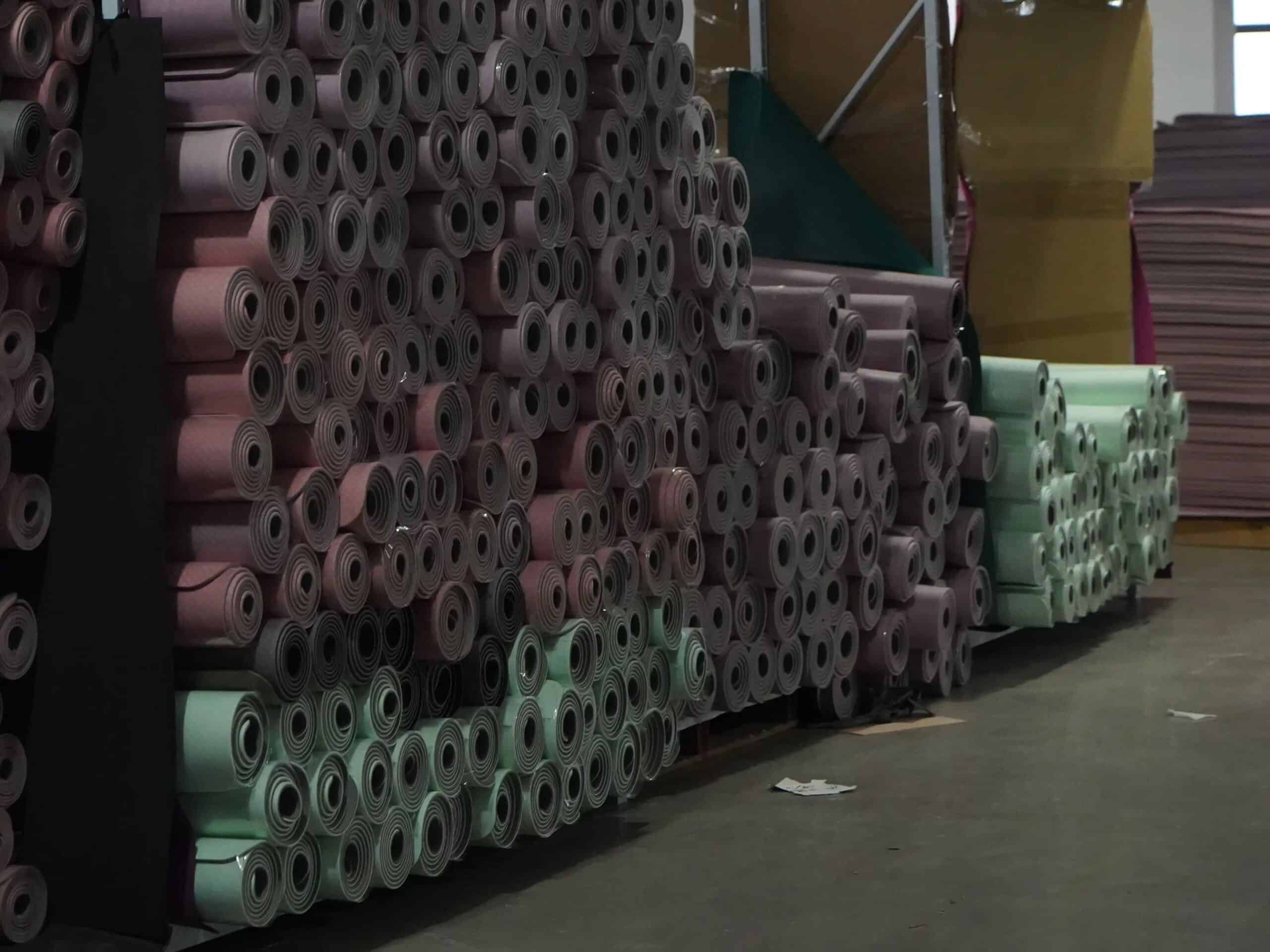 Bulk finished natural rubber yoga mat rolls stored in a climate-controlled warehouse.